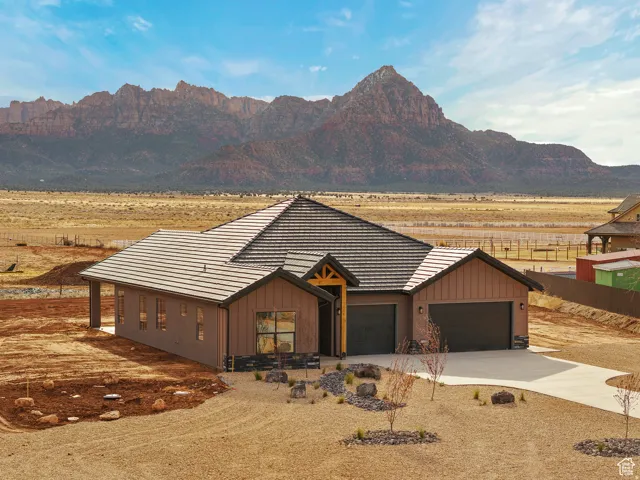 View of front of home featuring concrete driveway, board and batten siding, a tile roof, and an attached garage