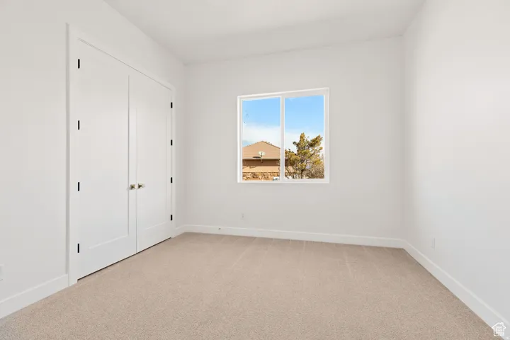 Unfurnished bedroom with light carpet and a closet