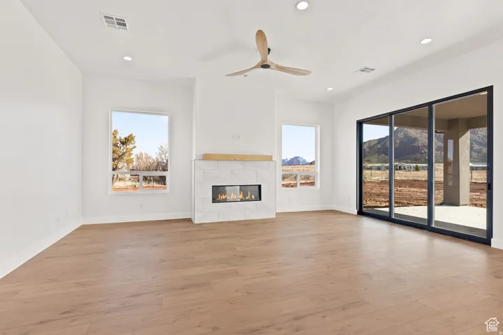 Unfurnished living room with a fireplace, light wood-type flooring, a ceiling fan, and recessed lighting