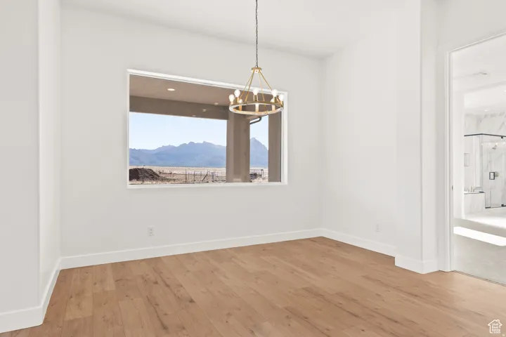 Unfurnished dining area with light wood-type flooring, suspended lighting, and a mountain view