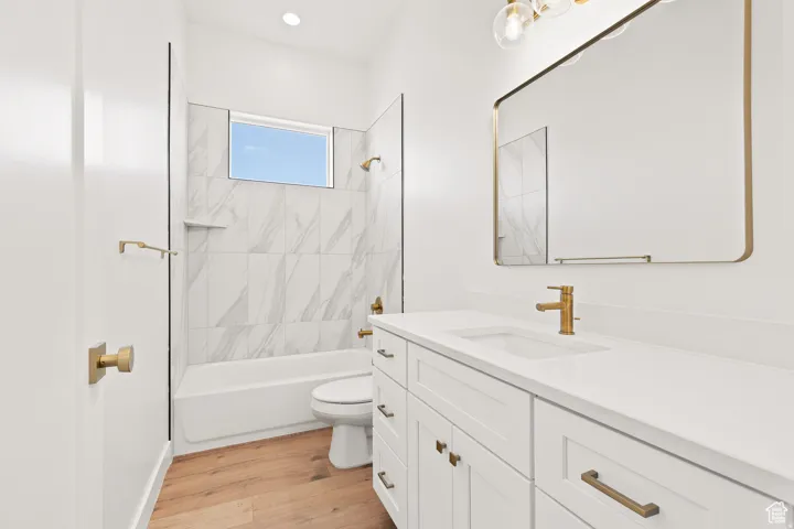 Full bathroom with vanity, washtub / shower combination, and light wood finished floors