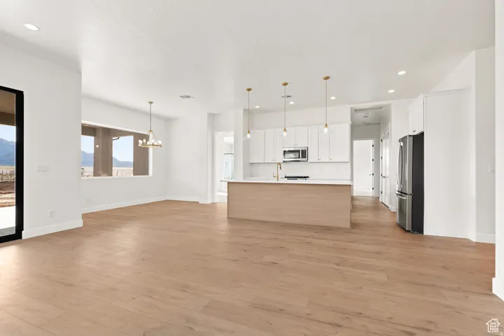 Kitchen with open floor plan, light countertops, stainless steel appliances, light wood-style flooring, and two tone cabinets
