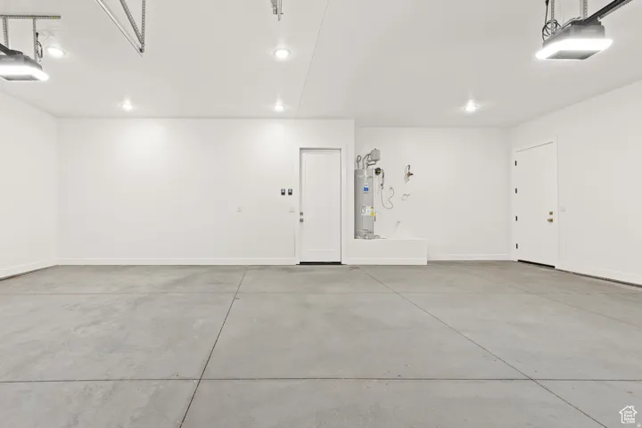 Garage featuring strapped water heater and a garage door opener