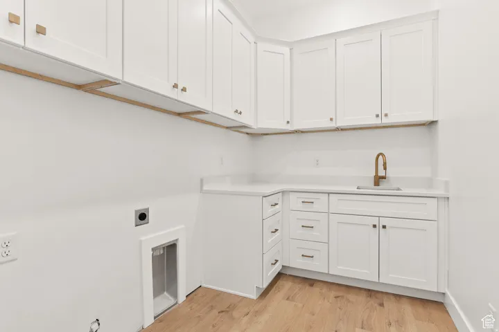 Laundry room with light wood-style flooring, cabinet space, and hookup for an electric dryer
