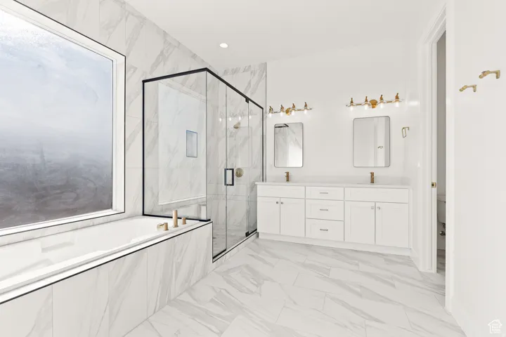 Full bath featuring a marble finish shower, double vanity, a garden tub, light marble finish flooring, and recessed lighting