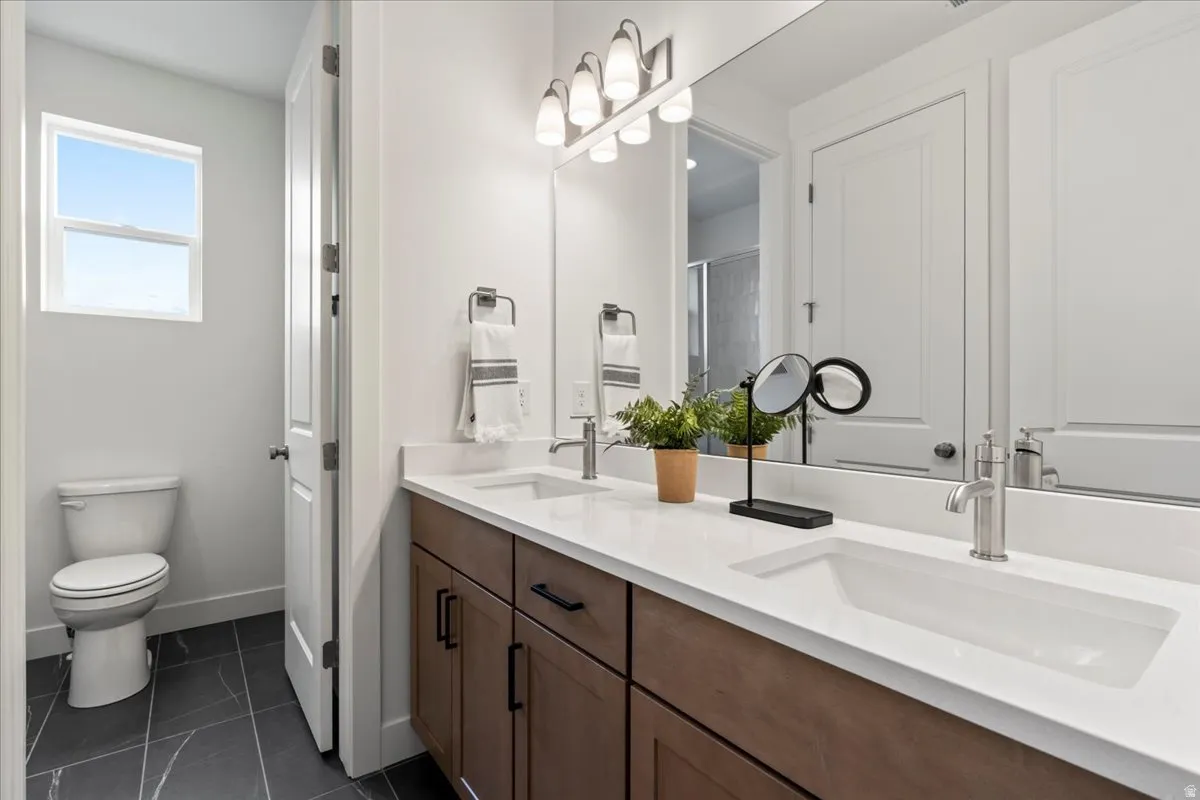 Full bath featuring double vanity and dark tile patterned floors