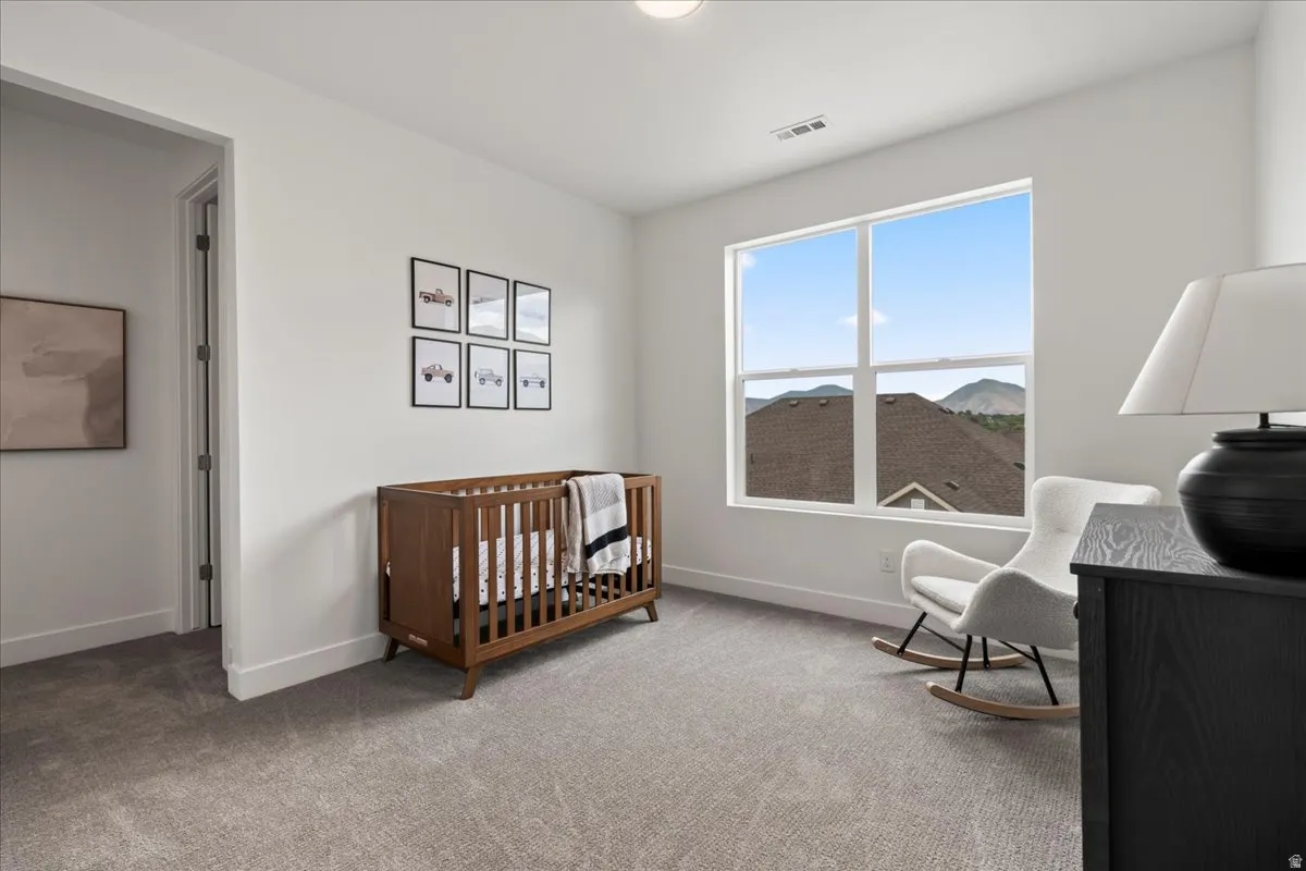 Carpeted bedroom featuring a nursery area and baseboards, walk in closet and ensuite bath