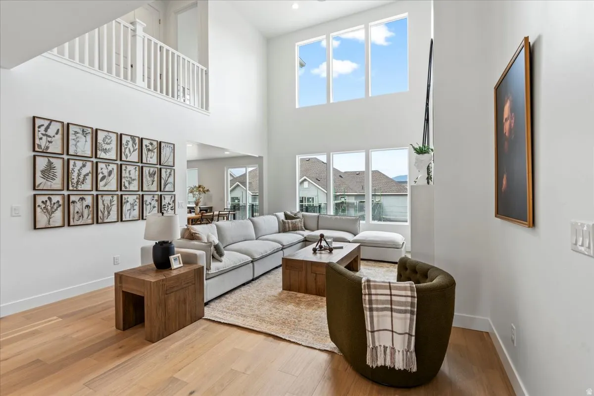 Living room with light wood-style floors, recessed lighting, and a high ceiling