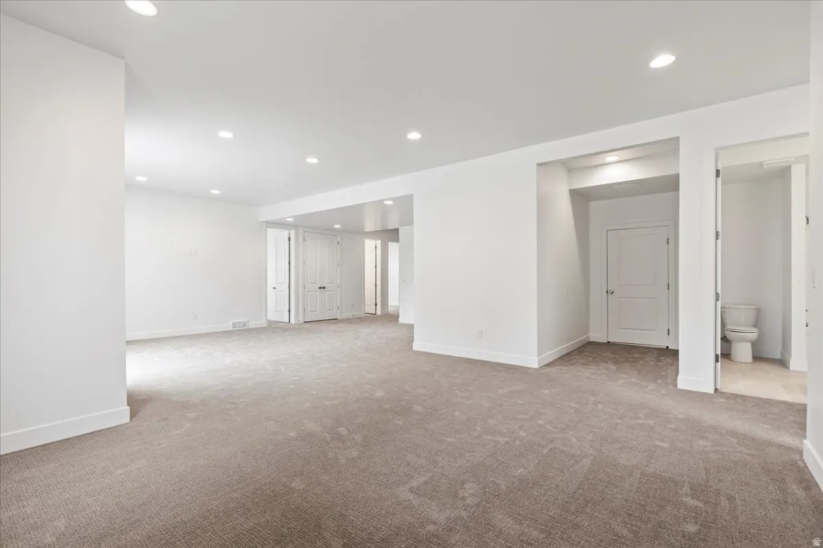 Great room with recessed lighting and carpet. Entry to massive storage/flex space under suspended garage slab.