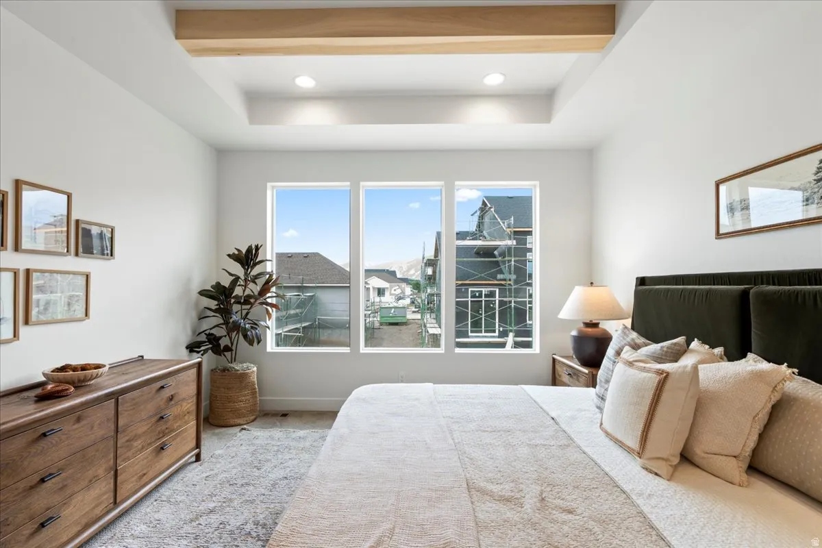 Primary bedroom with carpet, beamed ceiling, recessed lighting, and a tray ceiling