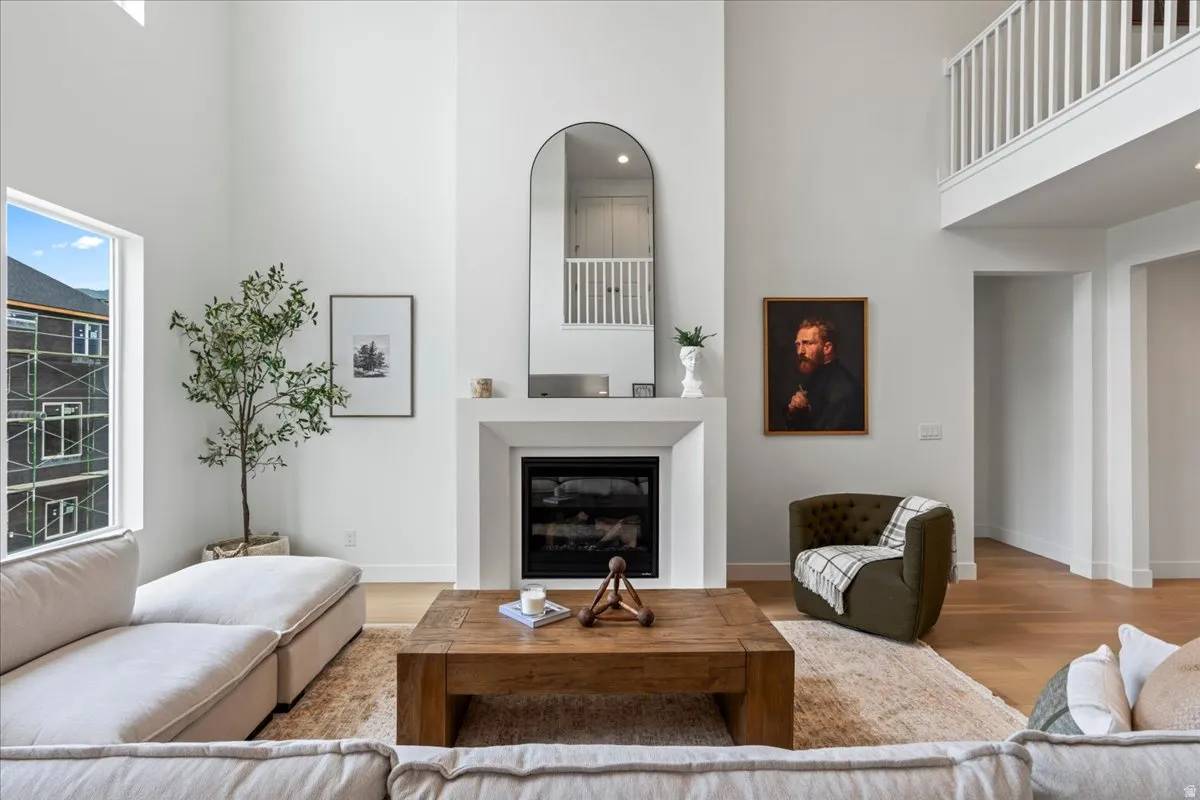 Living area featuring a high ceiling, a glass covered fireplace, and light wood-style flooring