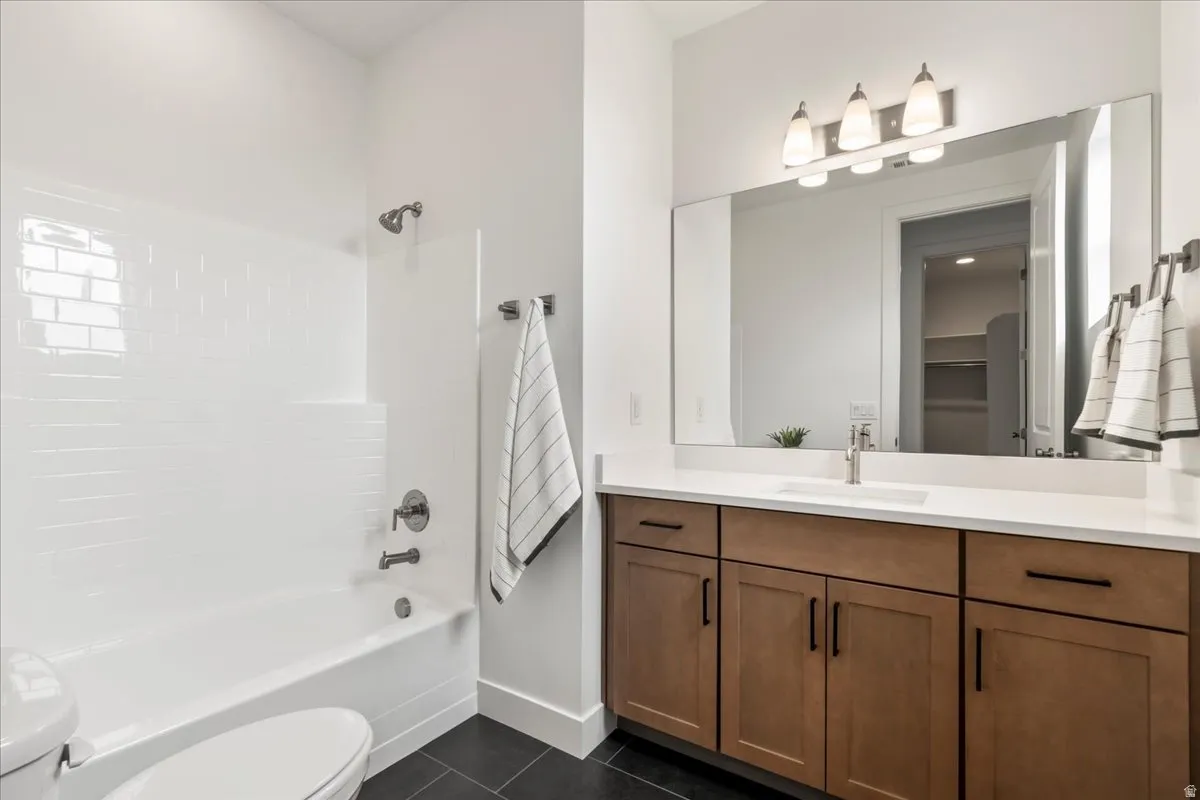 Full bath with vanity, dark tile patterned floors, and shower / bath combination