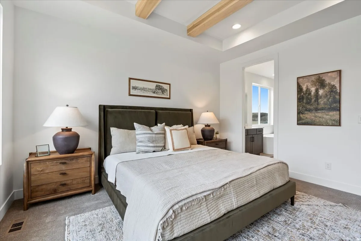 Primary bedroom featuring carpet flooring, beamed ceiling, recessed lighting, and ensuite bathroom