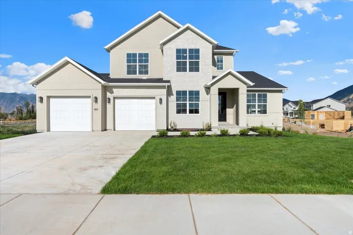 View of front of home featuring a mountain view, driveway, a front lawn, brick and stucco siding