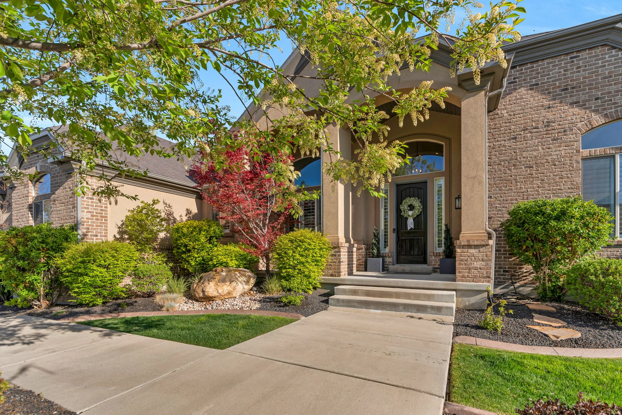 Stately brick and stucco exterior featuring an arched entryway with stone columns