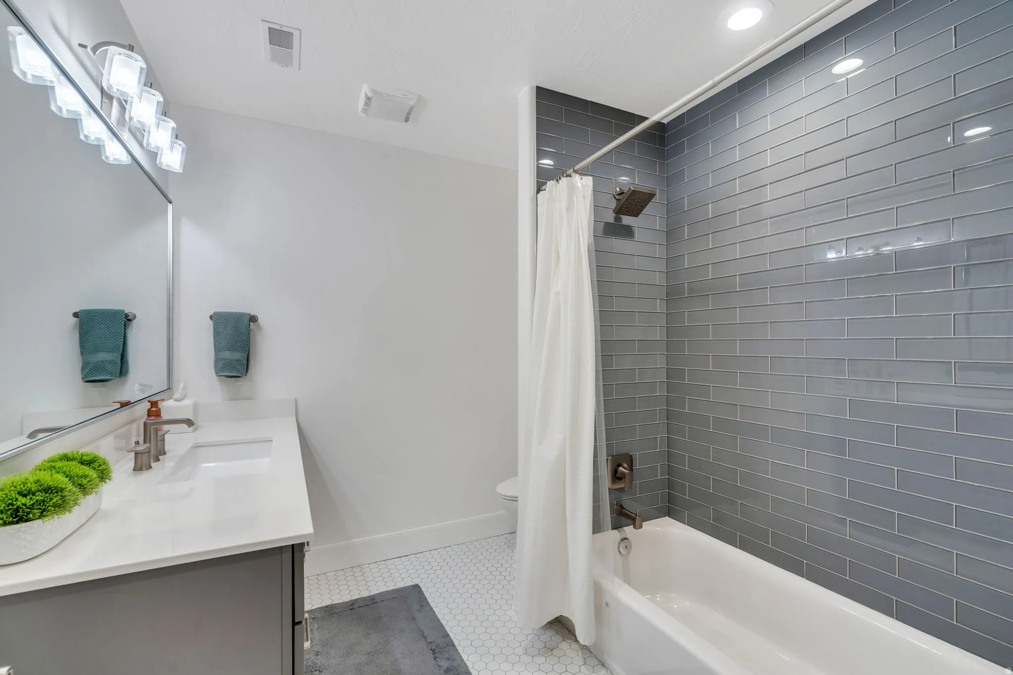 Downstairs Full bathroom, two of two with vanity, shower / bathtub combination,  tile floors, and recessed lighting