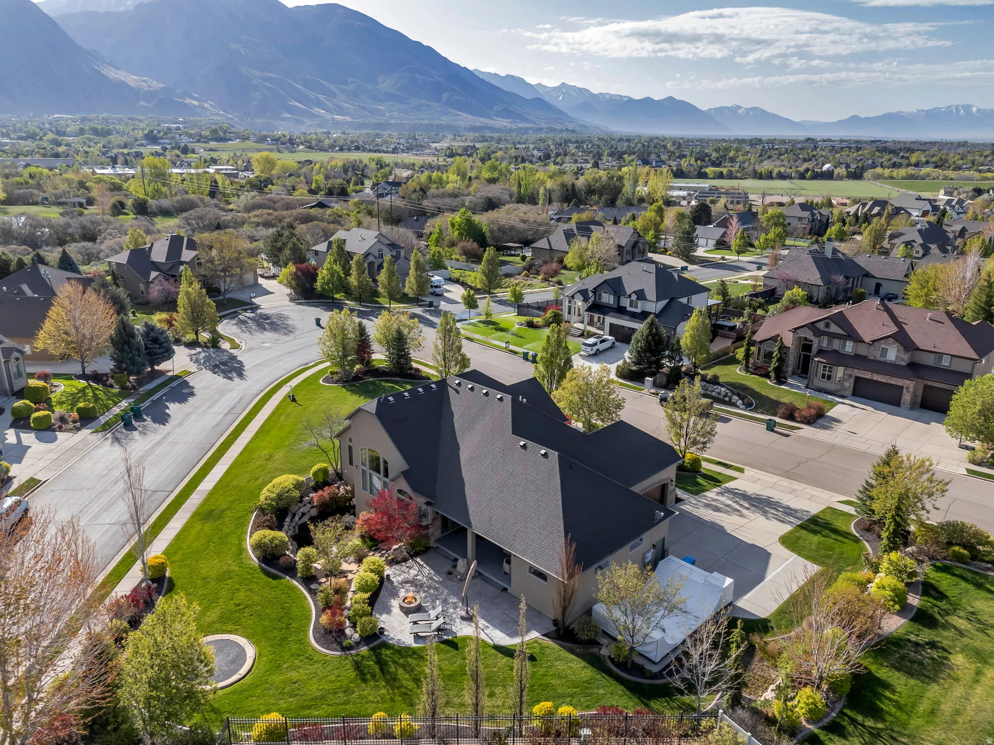 Expansive property featuring a meticulously manicured lawn, established landscaping, and a mountain backdrop