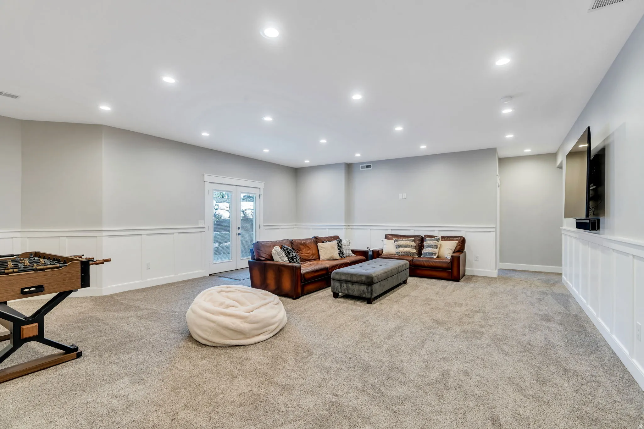 Downstairs family room featuring wainscoting, recessed lighting, carpet, and walk-out