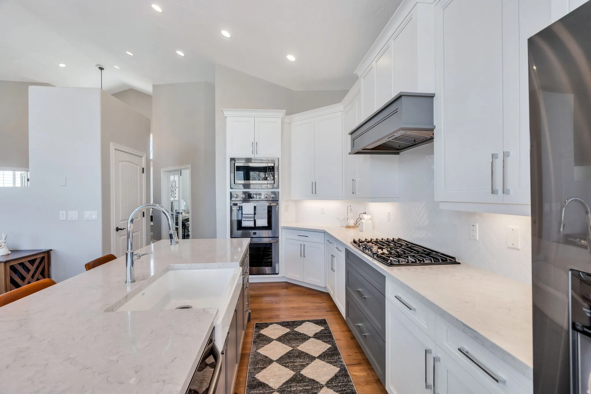 Kitchen with custom cabinetry, backsplash, quartz  counters, and stainless steel appliances