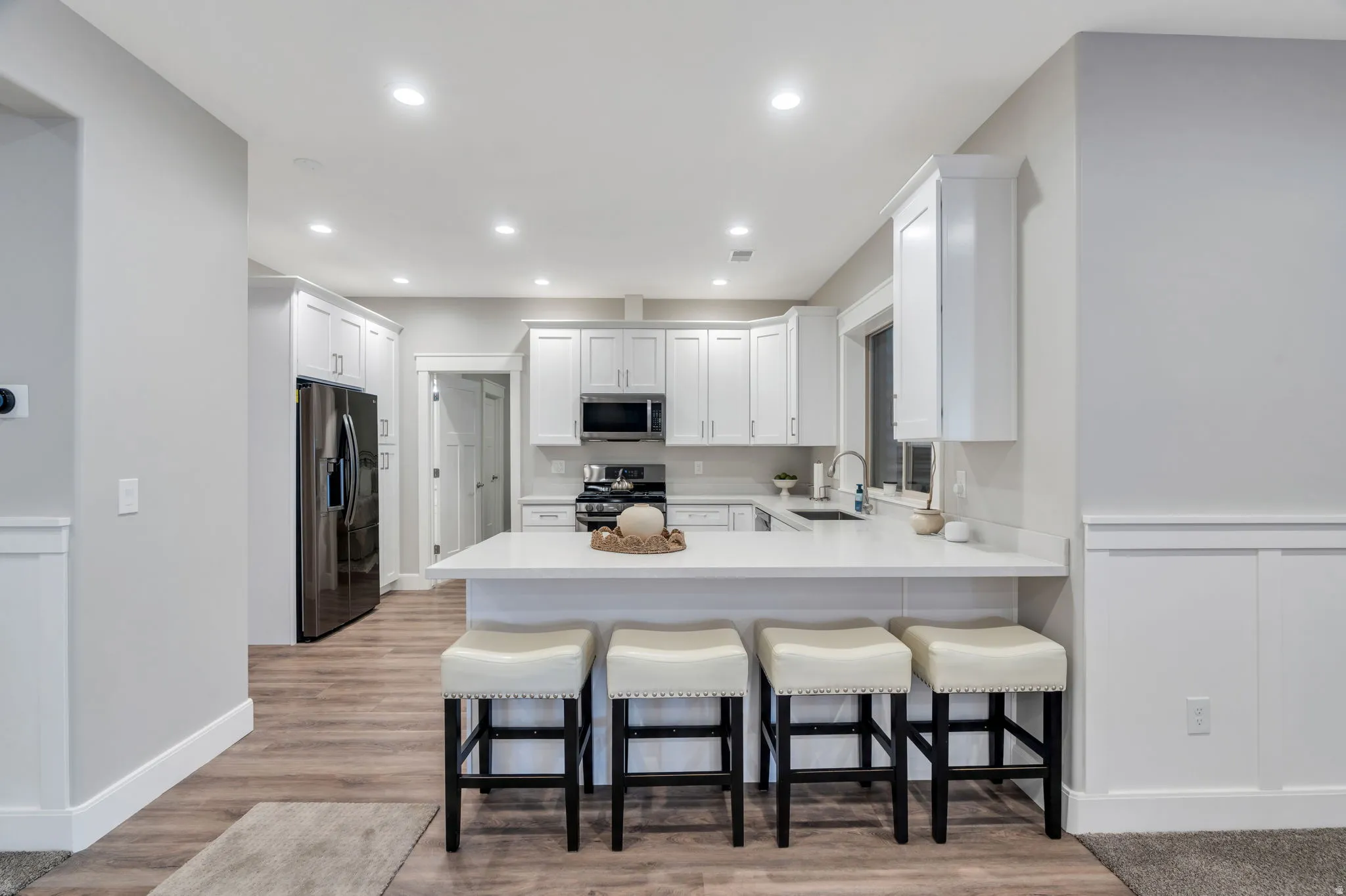 Downstairs Kitchen with a breakfast bar, white cabinetry, LVP flooring, and stainless steel appliances