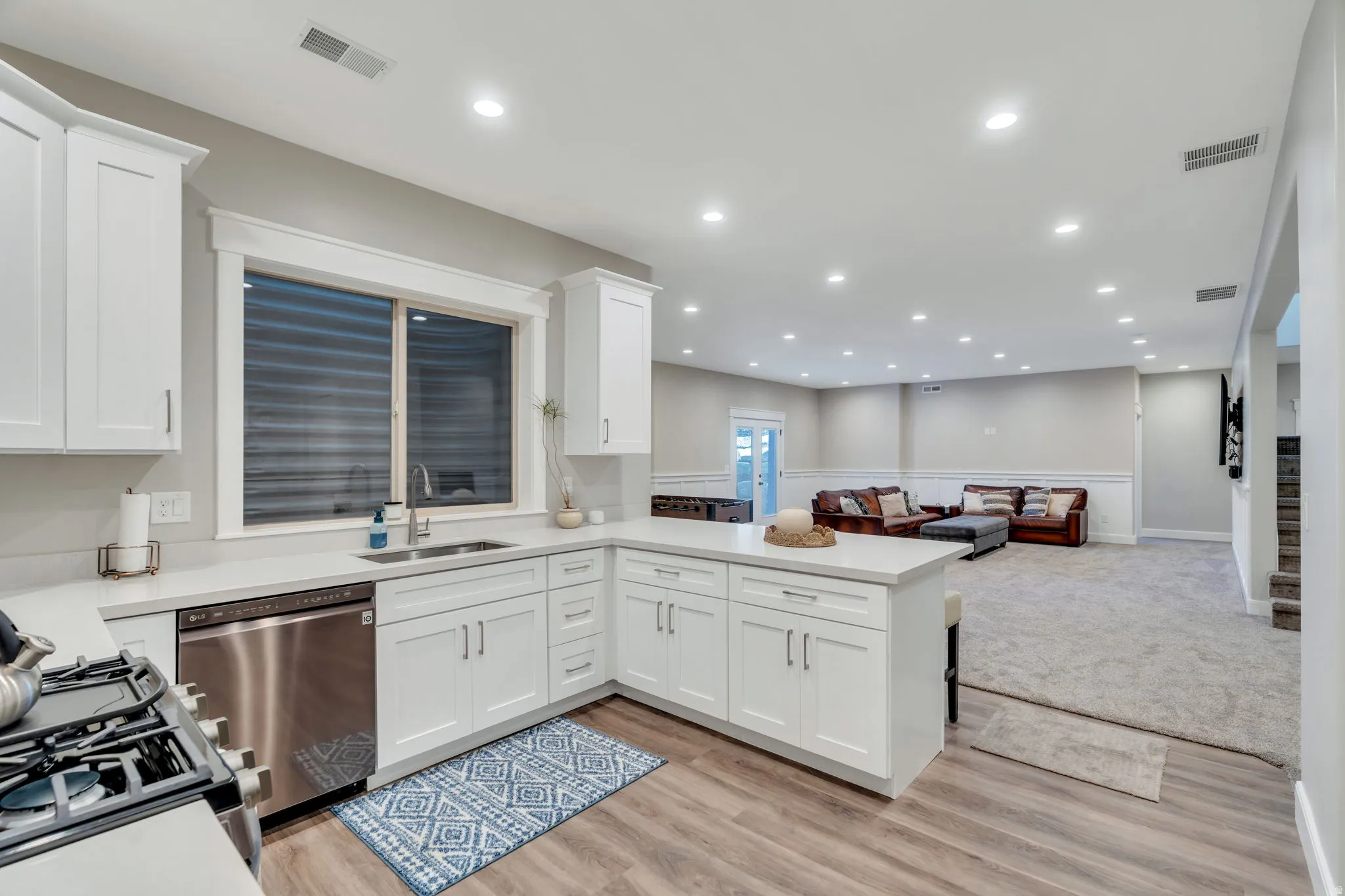 Kitchen with white cabinets, stainless steel appliances, open floor plan, recessed lighting, and a peninsula