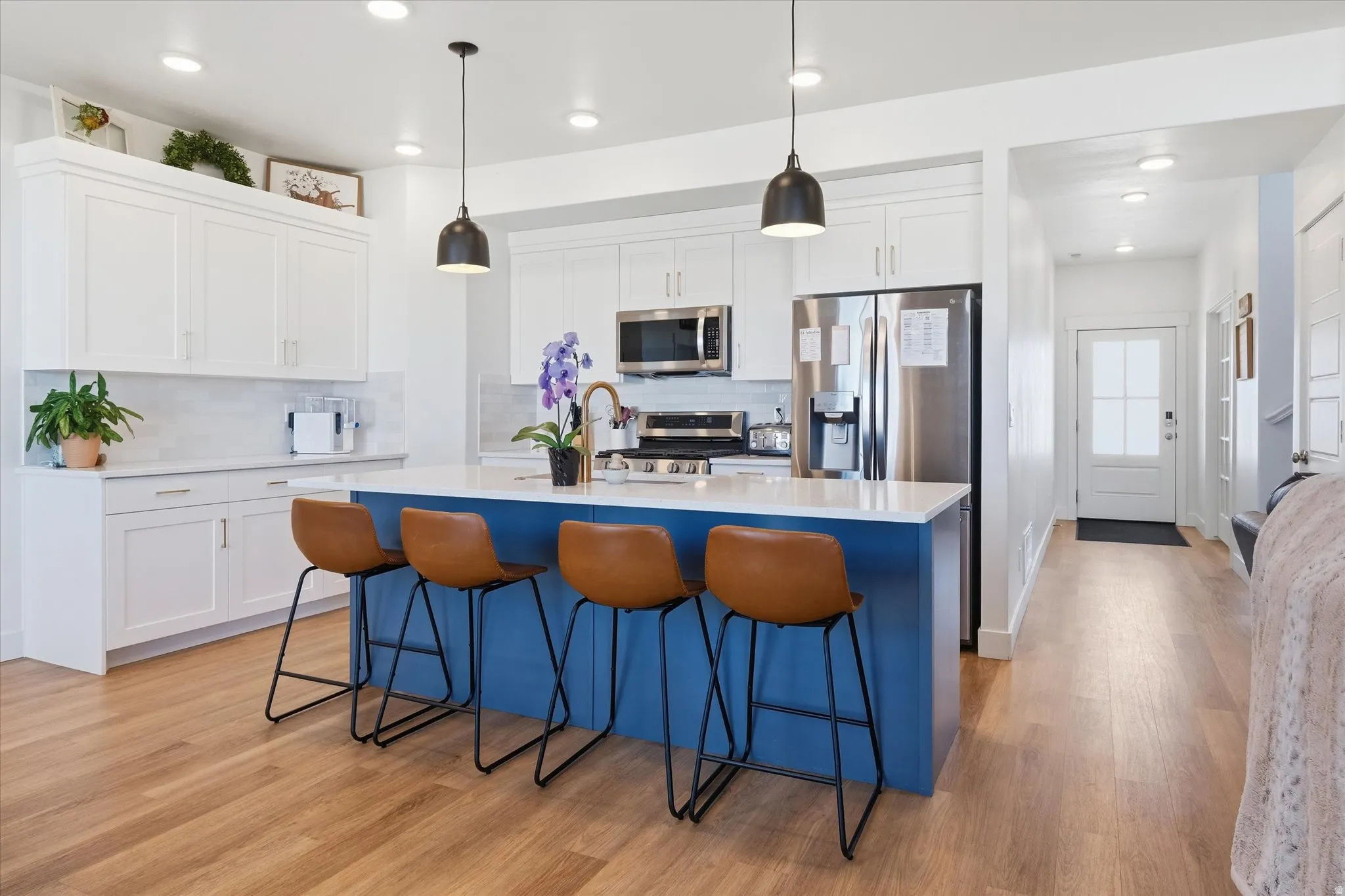 Kitchen featuring a breakfast bar area, a kitchen island with sink, white cabinetry, and light wood-style floors