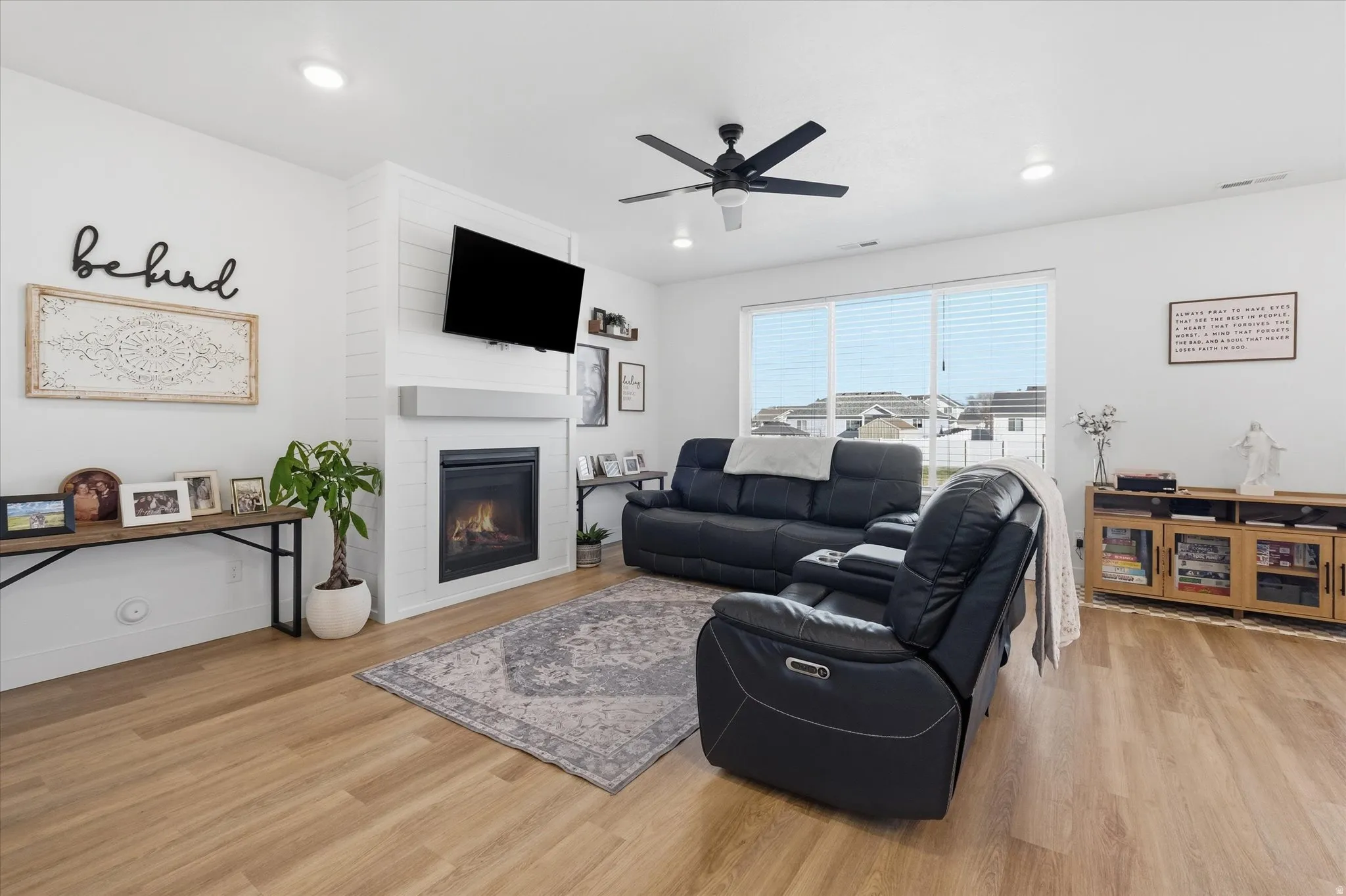 Living room with light wood-style floors, a ceiling fan, and a fireplace