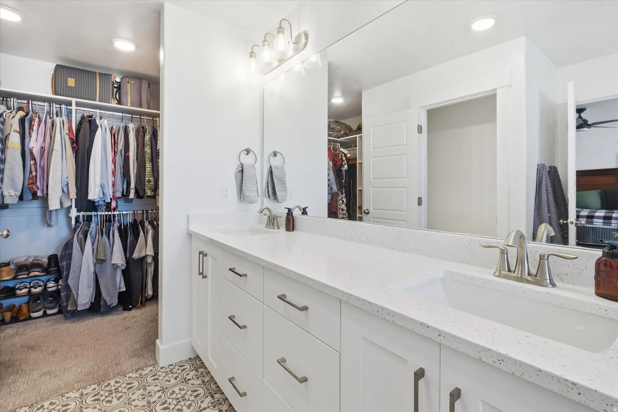 Primary Bathroom featuring a walk in closet, double vanity, light carpet, and recessed lighting
