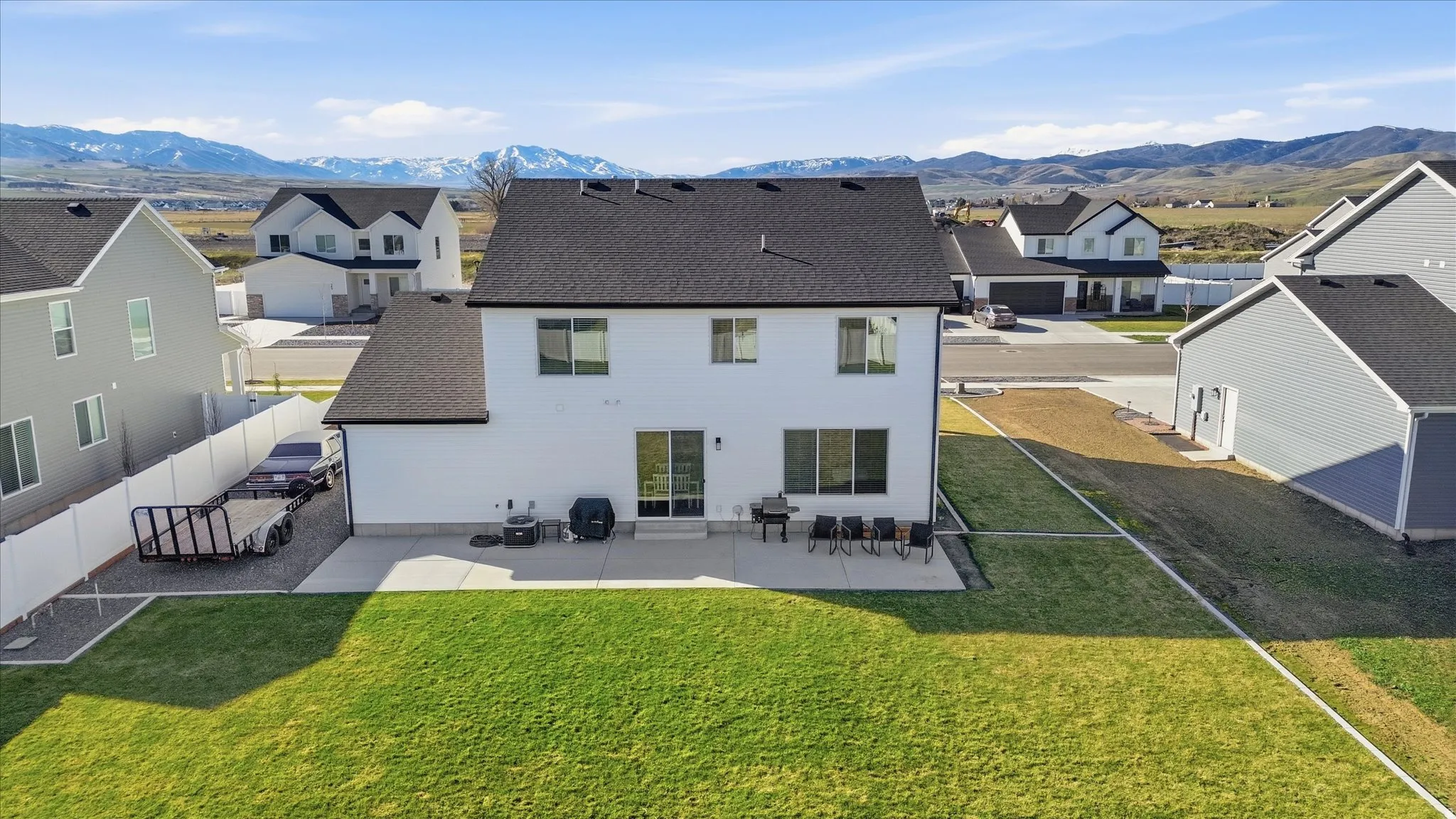 Back of property featuring a shingled roof, a residential view, a patio area, a yard, and a mountain view