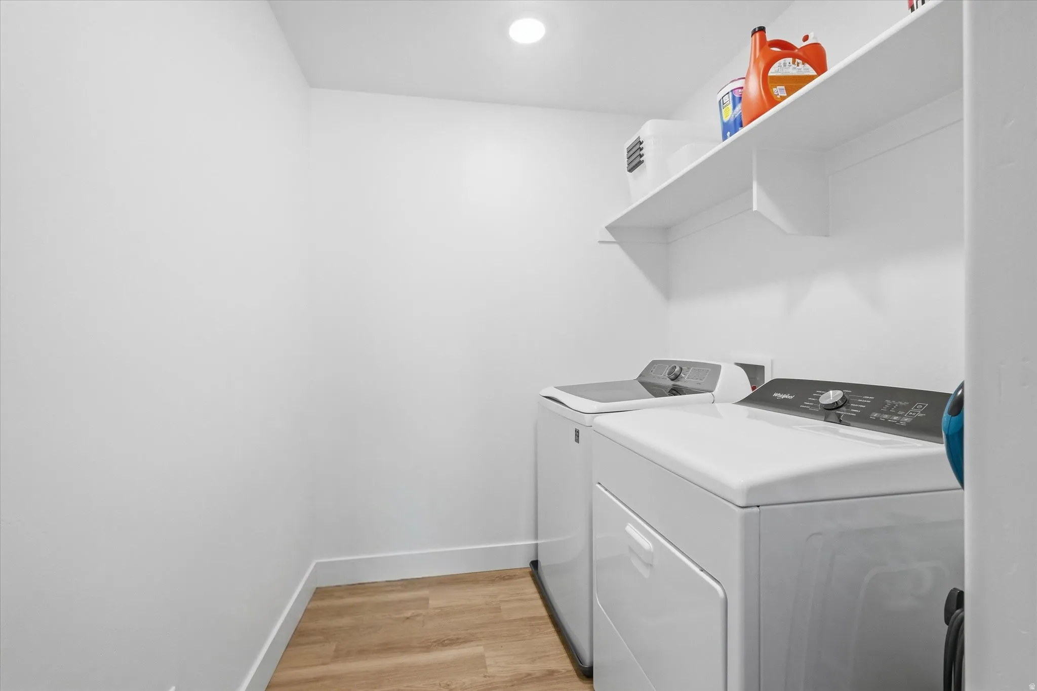 Laundry area with light wood-type flooring, washing machine and dryer, and recessed lighting