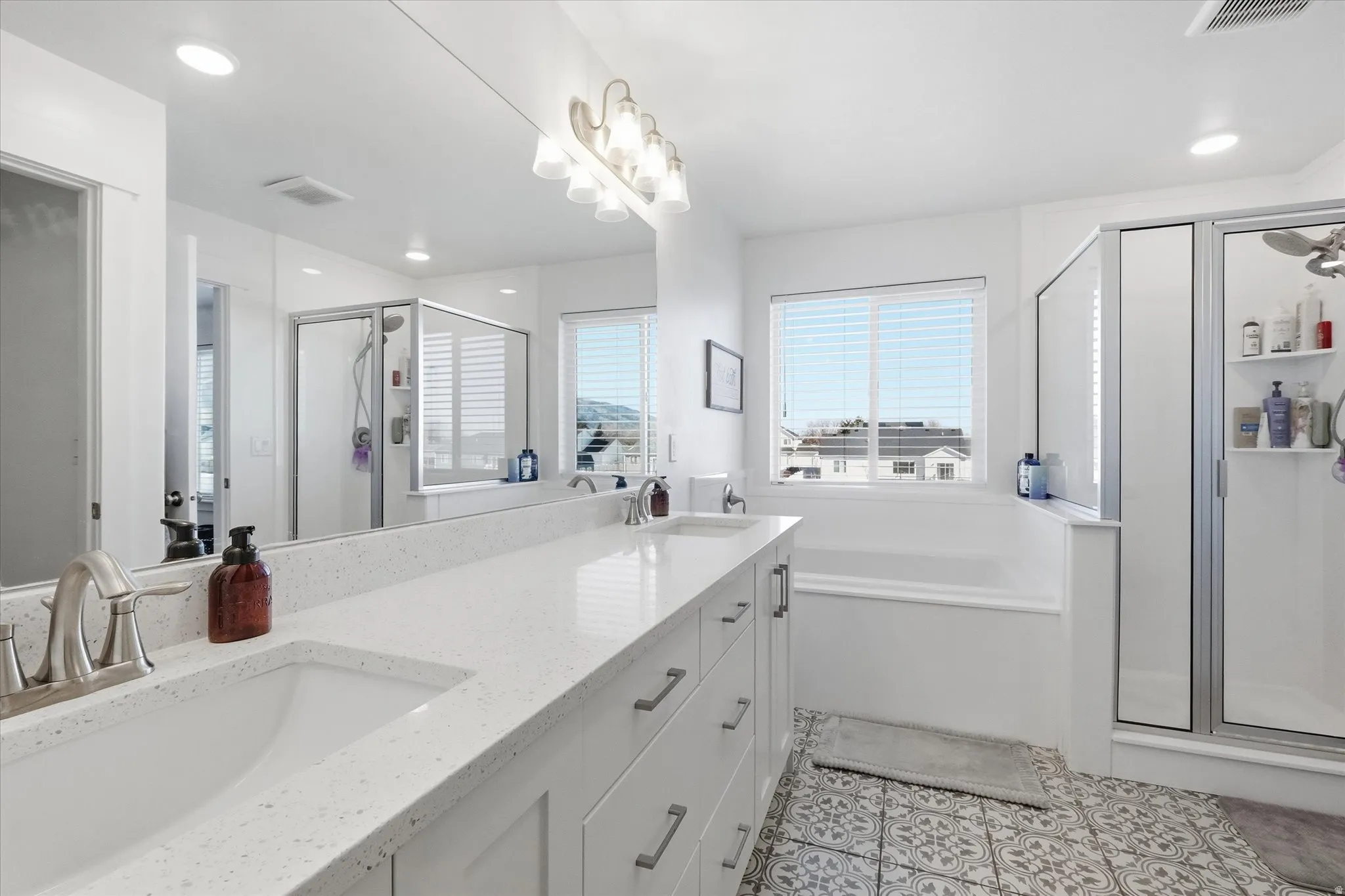 Primary Bathroom featuring a shower stall, double vanity, a garden tub, and recessed lighting