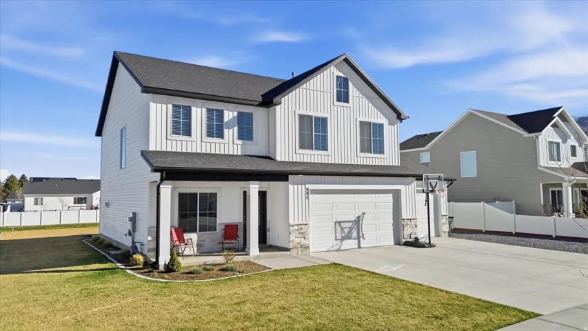 Modern inspired farmhouse with board and batten siding, covered porch, a garage, concrete driveway, and roof with shingles