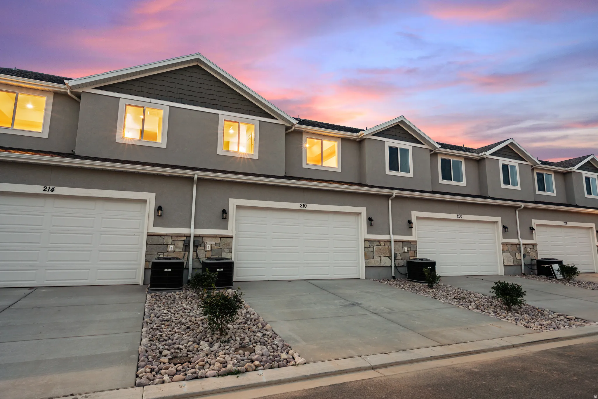 Multi-level townhome-style residences featuring attached garages, stucco exteriors, and stone accents