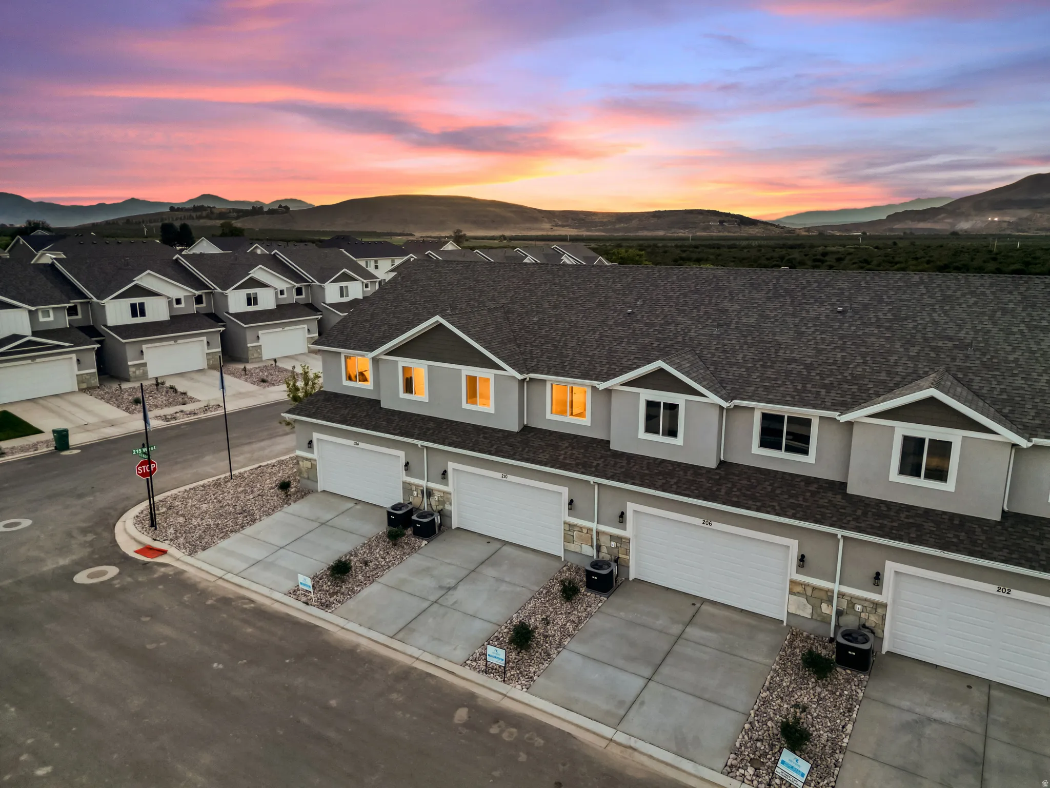 Newly constructed townhomes featuring attached garages, stone accents, asphalt shingle roofs, and concrete driveways