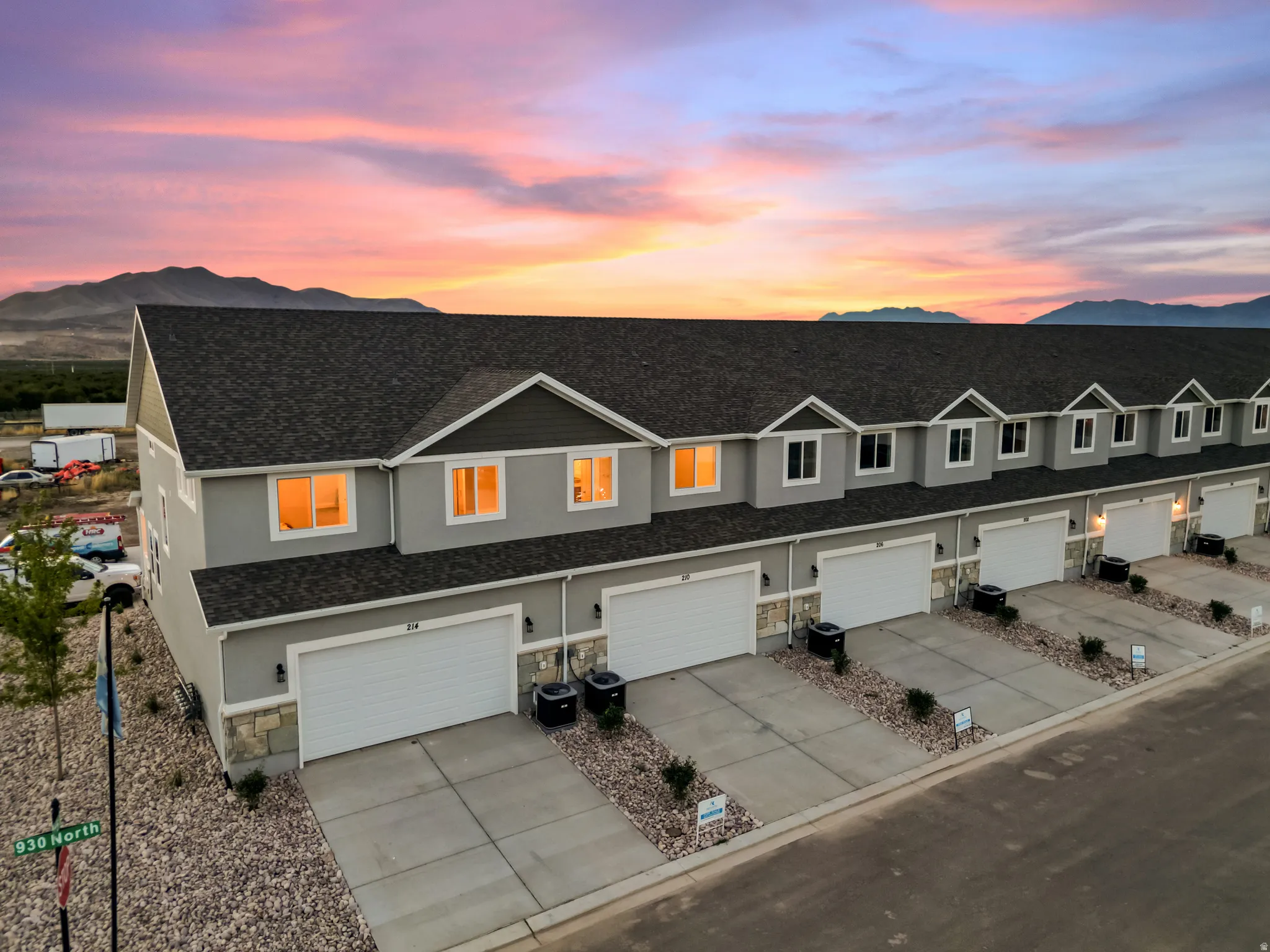 Modern townhome development featuring light gray stucco exteriors with stone veneer accents and dark shingled roofs
