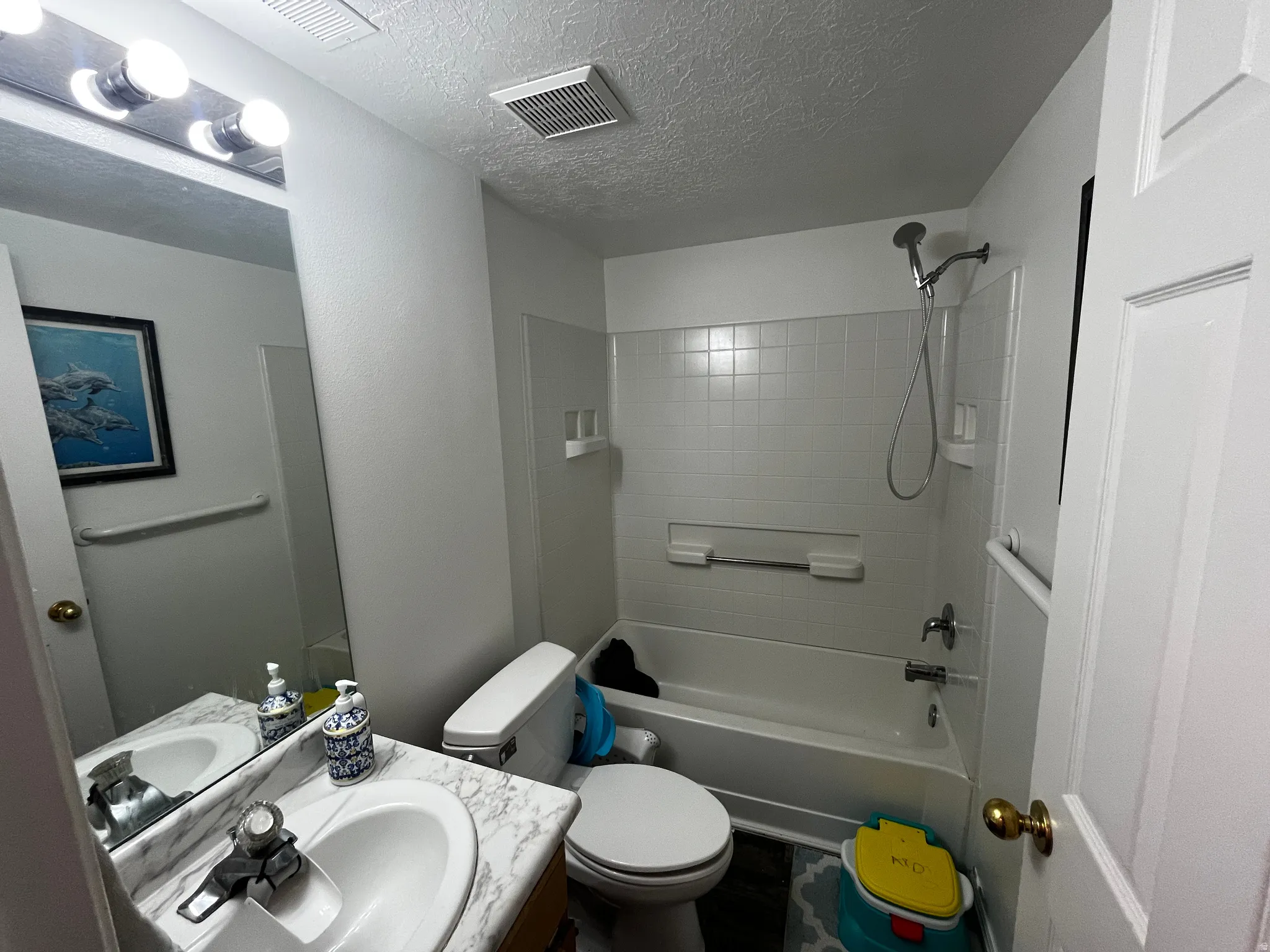 Full bath with vanity, a textured ceiling, and  shower combination
