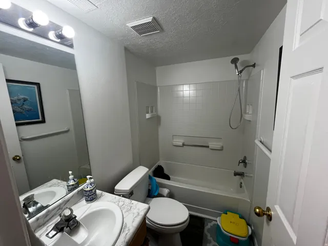 Full bath with vanity, a textured ceiling, and  shower combination