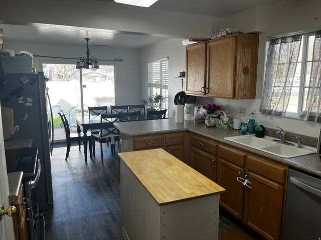 Kitchen with a peninsula, butcher block countertops, dishwasher, electric stove, and a center island