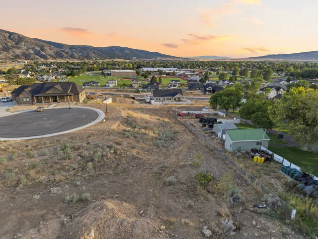 Expansive undeveloped lot with surrounding residential properties, a paved cul-de-sac, and distant mountain scenery