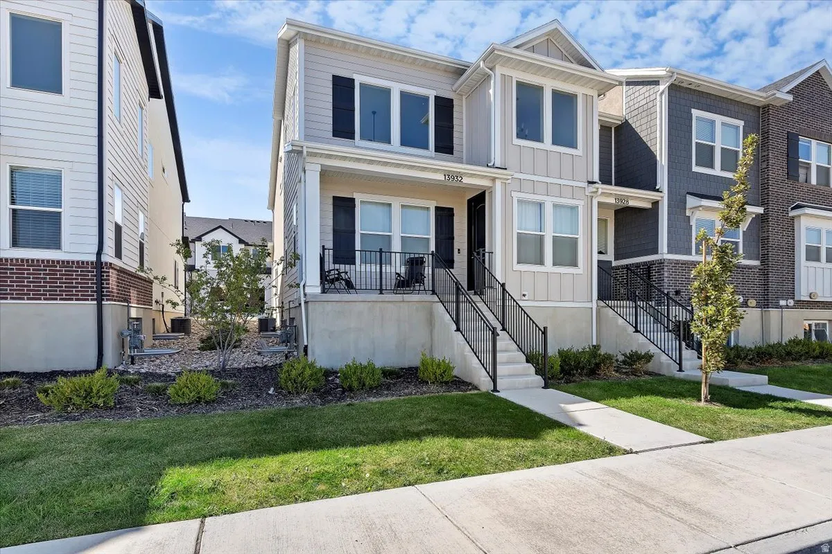 View of front of house with board and batten siding, a front yard, and covered porch
