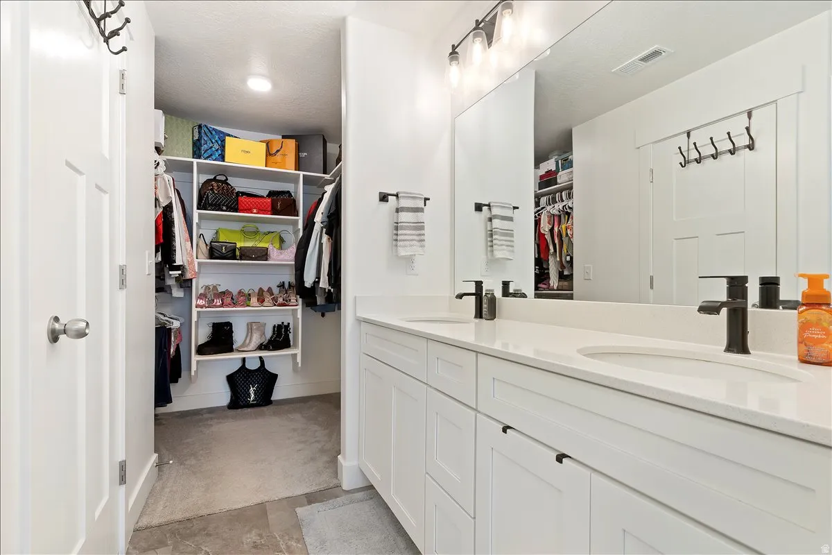 Full bathroom with double vanity and a spacious closet