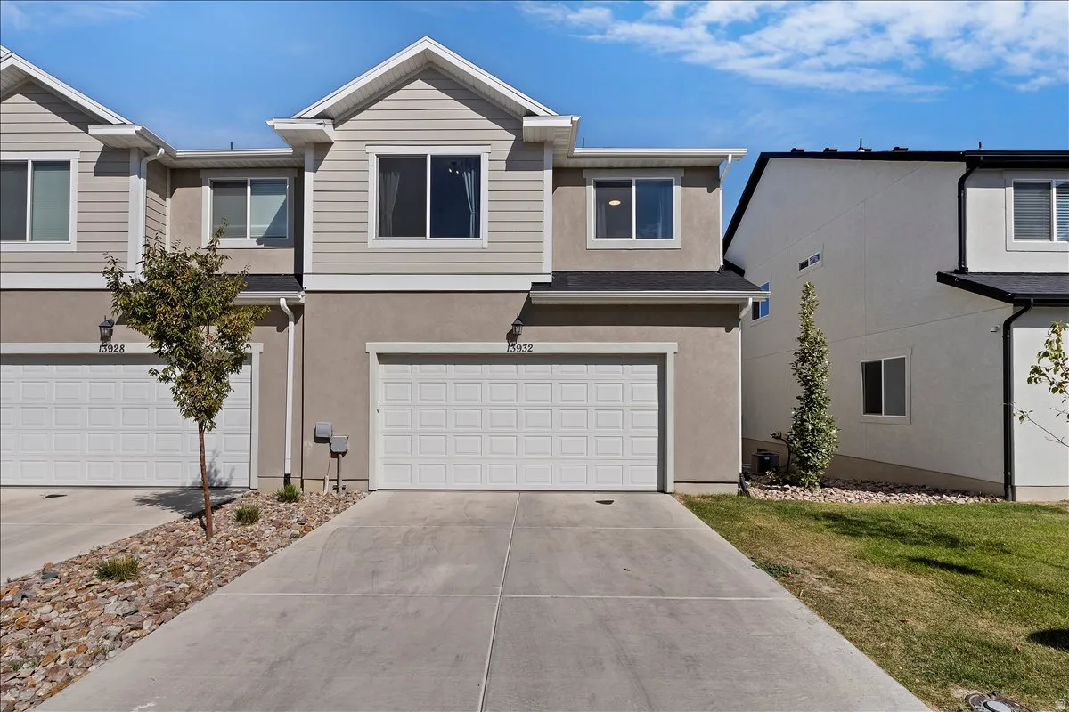 View of front facade featuring a garage, concrete driveway, and stucco siding