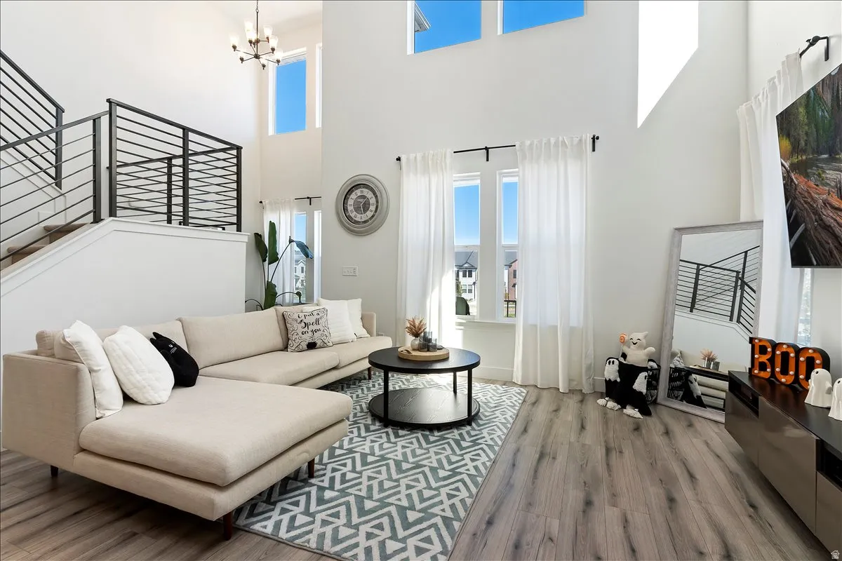 Living room with wood finished floors, healthy amount of natural light, suspended lighting, and a high ceiling