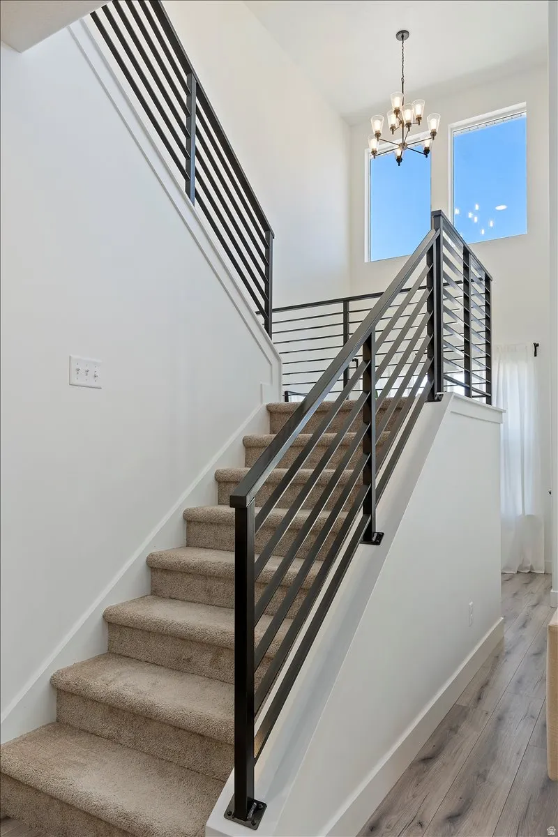 Staircase featuring wood finished floors and a chandelier