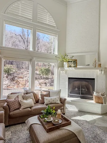 Living area featuring a brick fireplace, a high ceiling, plenty of natural light, and ornamental molding