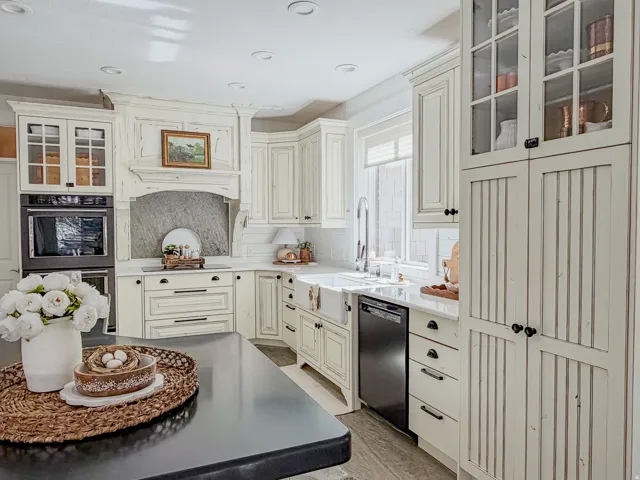 Kitchen with glass fronted cabinets, double oven, dishwasher, light wood-type flooring, and light stone countertops