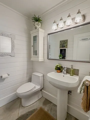 Half bath with wood walls and concrete flooring