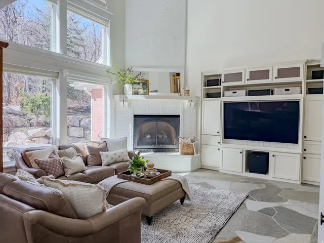 Living area with a high ceiling, light stone finish flooring, and a fireplace
