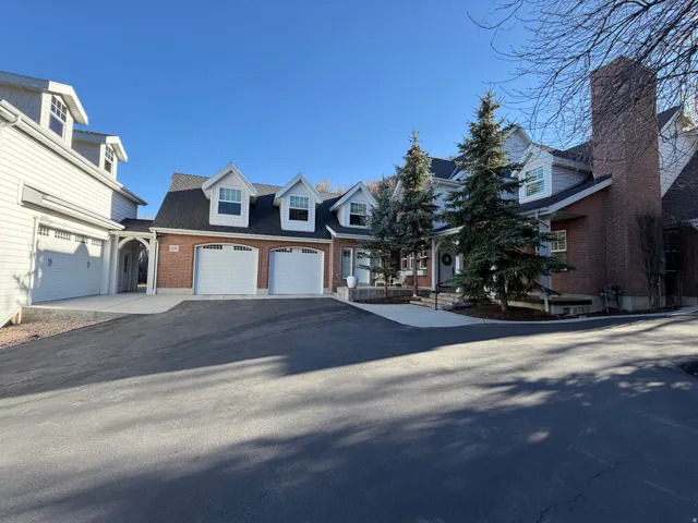 Brick and siding exterior featuring multiple dormer windows, a prominent brick chimney, and mature evergreen trees
