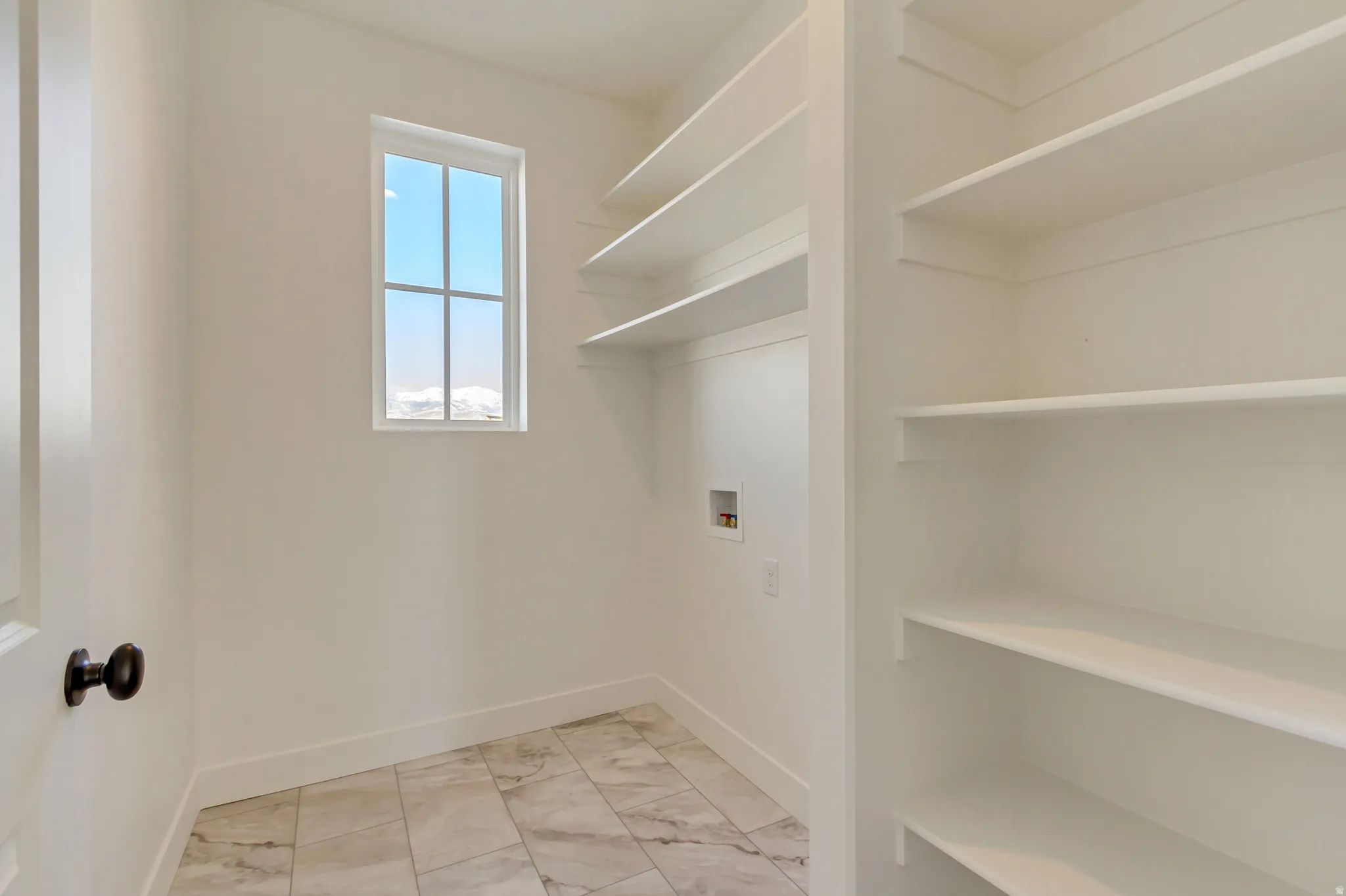Laundry area featuring hookup for a washing machine and light marble finish floors